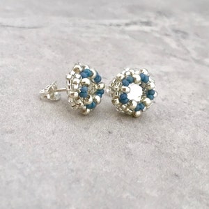 Puede incluir: Un par de pendientes de cuentas plateadas y azules con un dise&ntilde;o circular. Los pendientes son peque&ntilde;os y delicados.