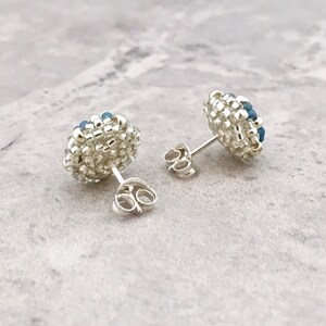 Puede incluir: Un par de pendientes de bot&oacute;n de plata con racimos de cuentas azules y blancas.