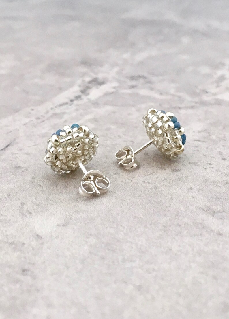 Puede incluir: Un par de pendientes de bot&oacute;n de plata con racimos de cuentas azules y blancas.