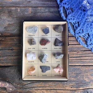 May include: A selection of rocks and minerals presented in a compartmentalised box. The box features specimens labelled "Granite," "Calcite," "Flint," "Zinc Ore," "Jasper," "Iron Ore," "Quartz," "Ore," "Lava," "Copper Ore," "Slate," and "Gypsum."