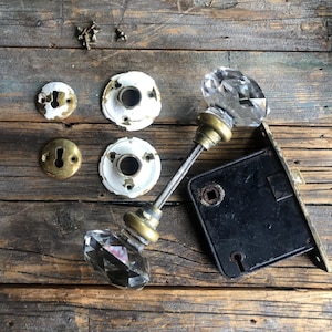 May include: Antique door hardware set with a crystal doorknob, a metal latch, and four porcelain escutcheons.