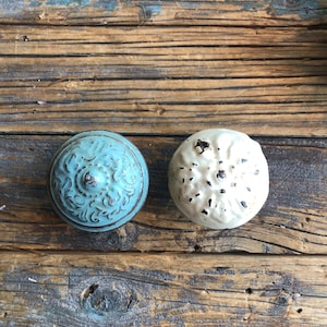 May include: Two decorative knobs, one in a light blue with a floral design and the other in white with a distressed finish.