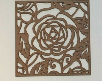 May include: A square, laser-cut wooden panel featuring a rose design. The panel is a warm brown color, with the rose and surrounding leaves and vines cut out, creating a negative space. The design is centered on the panel.