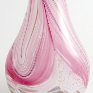 May include: Pink and white glass vase with swirling patterns. The vase has a pear-shaped body and a wide opening.
