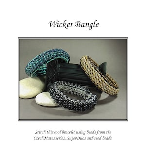 May include: Four beaded bracelets in different colors and patterns, including teal, gold, black, and silver. The bracelets are arranged on a gray background with rocks.