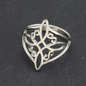 May include: A silver ring with a delicate, intricate design featuring a stylized flower motif. The ring is made of metal and has a polished finish.