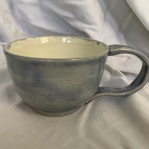 May include: A light blue ceramic mug with a white interior and a rounded handle.