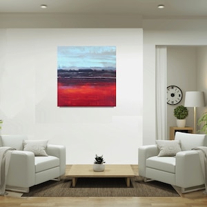 Può includere: Dipinto di paesaggio astratto con un gradiente di colori. L'opera presenta una base rossa vibrante, che sfuma in viola scuro, grigio e azzurro nella parte superiore. Il dipinto è esposto in un moderno salotto.