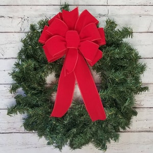 May include: A red velvet bow with a wired edge, tied on a green Christmas wreath.