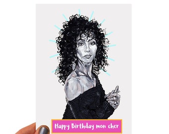 May include: A greeting card featuring a black and white portrait of a woman with dark, curly hair. The card has the text "Happy Birthday mon cher" in a pink and yellow banner.