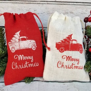 Pu&ograve; includere: Due sacchetti regalo in iuta con coulisse. Uno &egrave; rosso, l'altro naturale. Ogni sacchetto presenta un camion vintage che trasporta un albero di Natale, con "Merry Christmas" stampato sotto. Decorazioni festive natalizie.