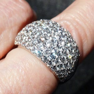 May include: A silver ring with a wide band covered in small, sparkling diamonds.