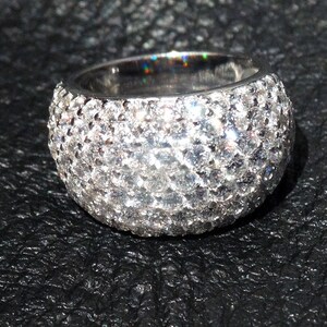 May include: A silver ring with a band of small, round, clear stones.