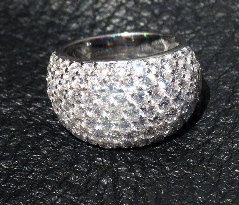 May include: A silver ring with a band of small, round, clear stones.