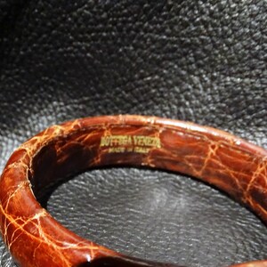 Pu&ograve; includere: Un braccialetto in pelle marrone con il testo "Bottega Veneta Made in Italy" in rilievo all'interno.