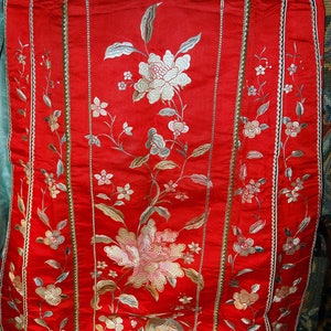 K&ouml;nnte beinhalten: Ein rotes Seidenstoffpanel mit gestickten Blumendesigns in Silber- und Goldfaden. Das Panel zeigt einen Vogel und Blumen und ist mit einem goldenen und silbernen Besatz eingefasst.