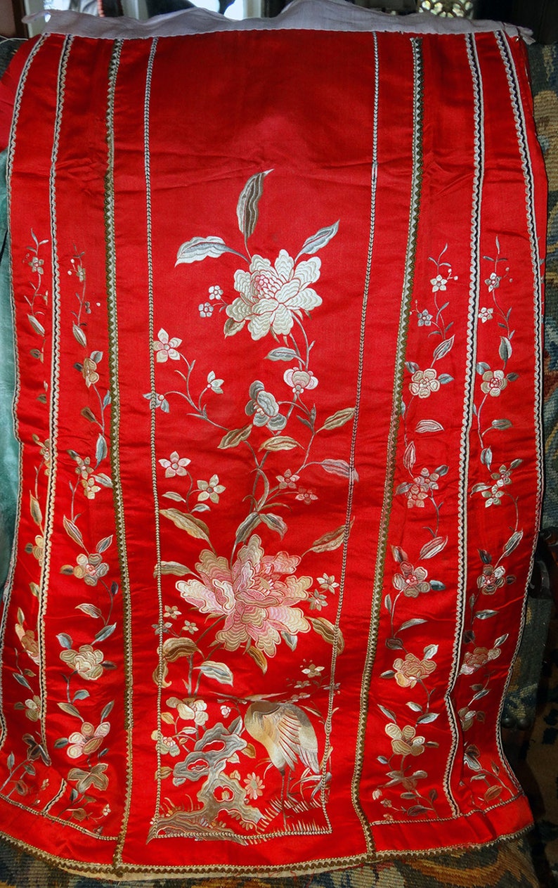 K&ouml;nnte beinhalten: Ein rotes Seidenstoffpanel mit gestickten Blumendesigns in Silber- und Goldfaden. Das Panel zeigt einen Vogel und Blumen und ist mit einem goldenen und silbernen Besatz eingefasst.