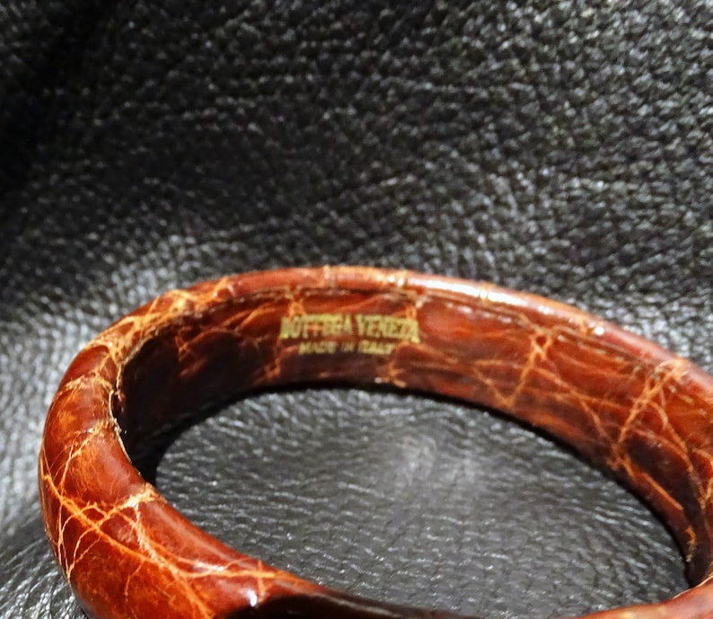 Pu&ograve; includere: Un braccialetto in pelle marrone con il testo "Bottega Veneta Made in Italy" in rilievo all'interno.