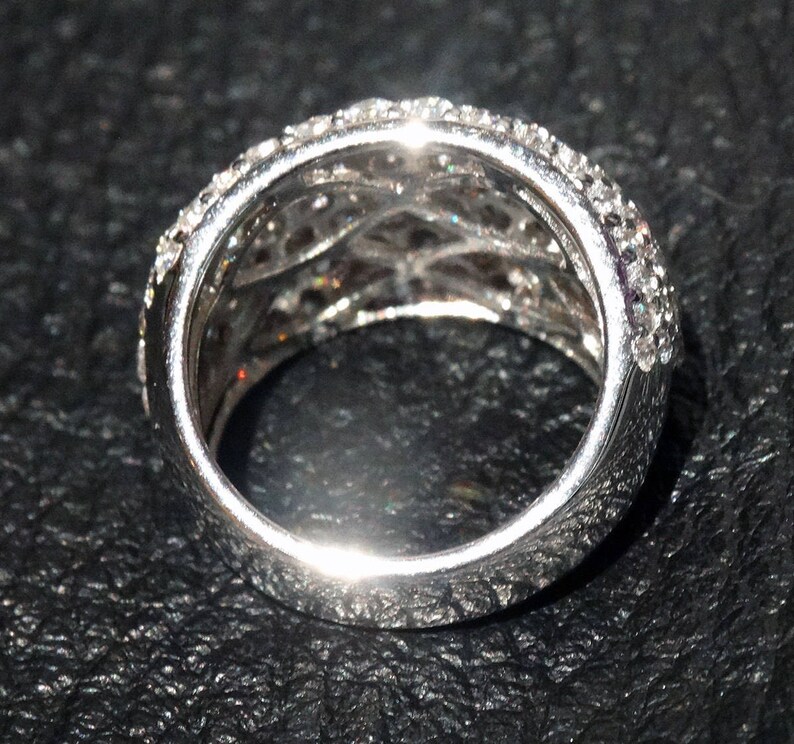 May include: A silver ring with a delicate, multi-layered design. The ring is set with small, clear stones that create a sparkling effect.