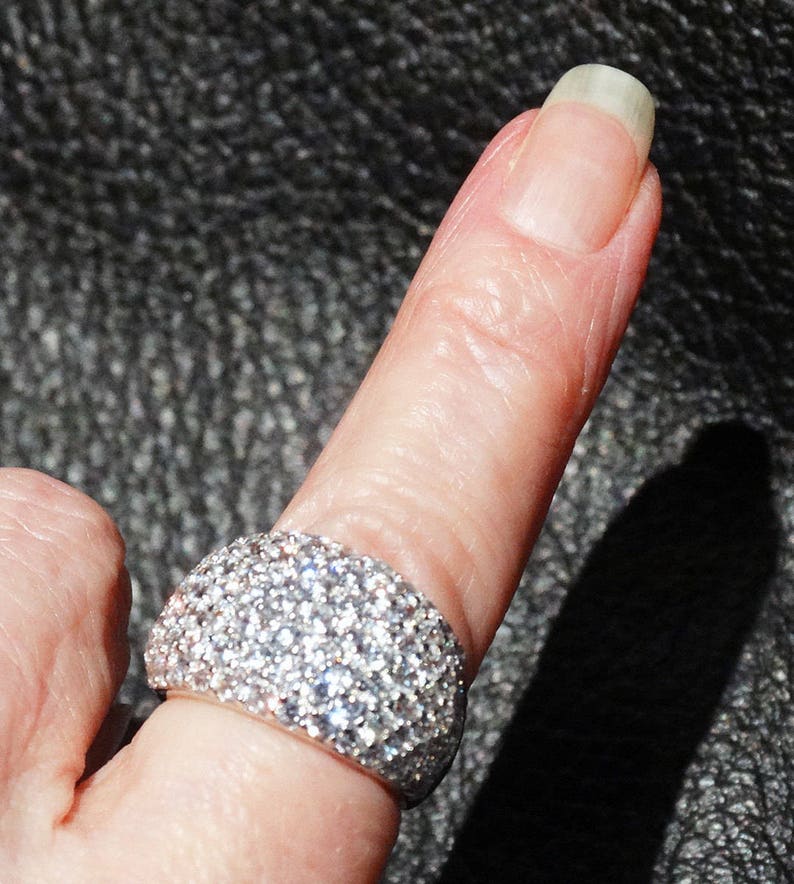 May include: A silver ring with a wide band covered in small, sparkling diamonds.