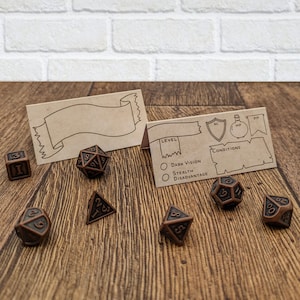 May include: A set of brown metal dice with black numbers, a blank card with a scroll design, and a card with a character sheet for a role-playing game. The character sheet includes the text "LEVEL", "DARK VISION", "STEALTH", "DISADVANTAGE", "AC", "HP", "CONDITIONS", and "DD".