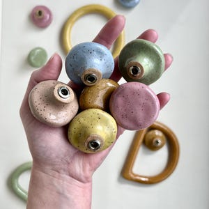 May include: A white ceramic mug with a black handle and the text "But First, Coffee" in a bold, black font. The mug is set against a blurred background, suggesting a cozy setting.