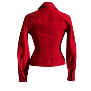 May include: A red corduroy jacket with a classic denim style. The jacket has a collared neckline, long sleeves, and a button-up front.