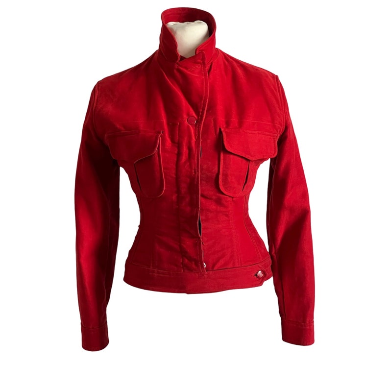 May include: A red velvet jacket with a high collar, long sleeves, and two large pockets on the front. The jacket has a button closure and a fitted waist.