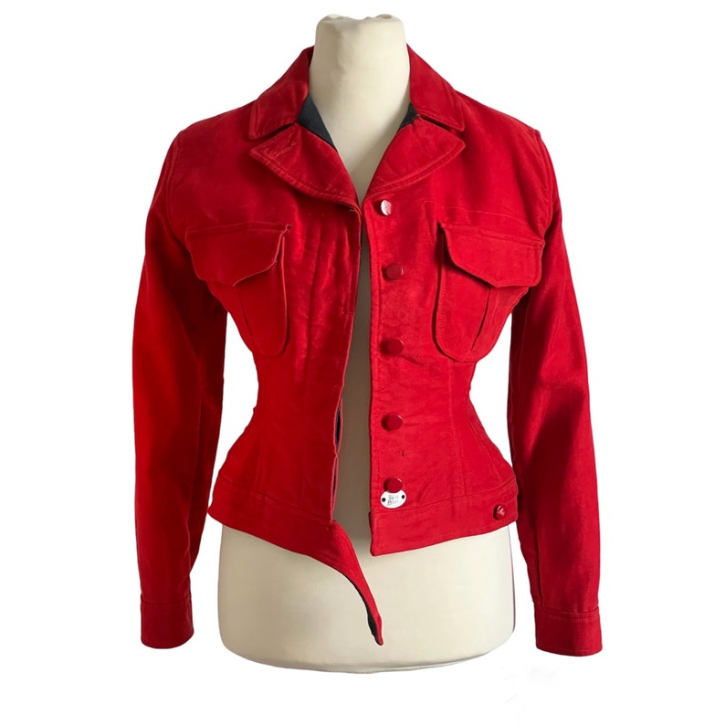 May include: A red, fitted jacket with a button-up front and two flap pockets. The jacket has a cinched waist and long sleeves.