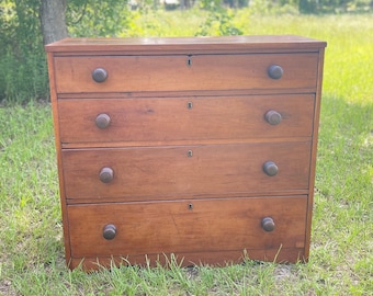 May include: A five-drawer wooden dresser with dark brown wood and brass knobs. The dresser is sitting on a green grassy lawn.