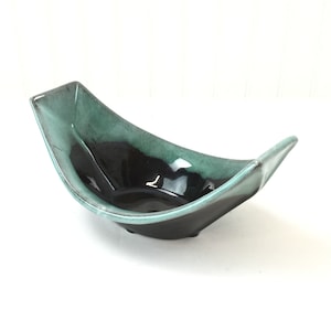 May include: A black and green ceramic serving bowl with a unique, angular shape. The bowl is glazed in a dark green and black color scheme.