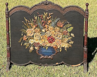 Può includere: Paravento antico per camino con sfondo nero e un'elaborata composizione floreale nei toni del giallo, rosso e arancione. Lo schermo ha una cornice ornata e gambe in legno marrone scuro. Alto circa 100 cm.