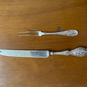 May include: A silver butter knife and fork set with an alligator design on the handles.