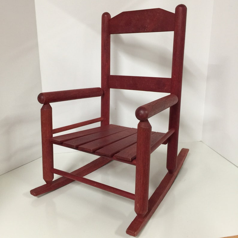 Puede incluir: Una silla mecedora de madera roja con un asiento de listones y un respaldo alto. La silla est&aacute; hecha de madera maciza y tiene un aspecto r&uacute;stico.