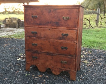 May include: A five-drawer dresser with a scalloped base. The dresser is made of wood and has a dark brown finish. The drawers have brass handles.