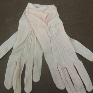 May include: A pair of white gloves with delicate lace detailing. The gloves are made of a soft, sheer fabric and have a classic, elegant design.