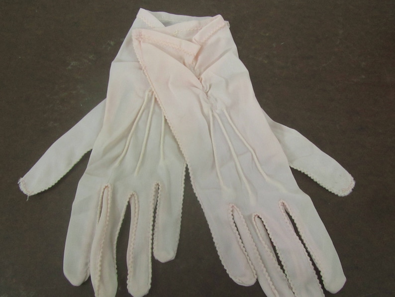 May include: A pair of white gloves with delicate lace detailing. The gloves are made of a soft, sheer fabric and have a classic, elegant design.