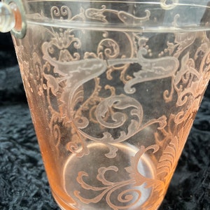 May include: A clear glass ice bucket with a silver handle. The bucket features a delicate etched floral design in a pale pink colour.