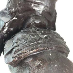 May include: Close-up of a dark brown wooden sculpture of a person riding a horse. The sculpture is detailed with intricate carvings and textures.