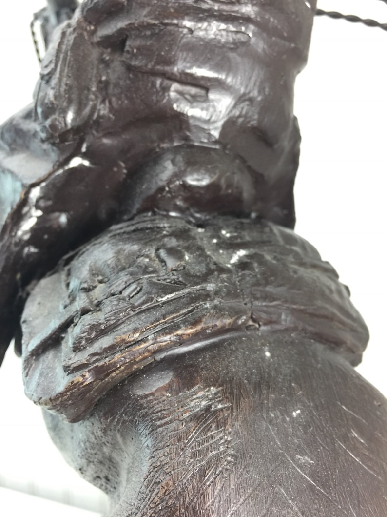 May include: Close-up of a dark brown wooden sculpture of a person riding a horse. The sculpture is detailed with intricate carvings and textures.