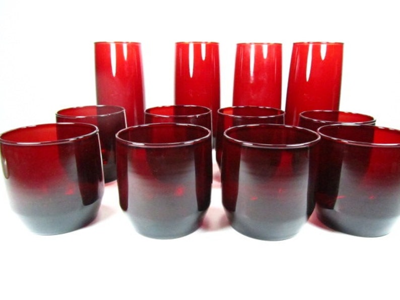 May include: Set of 12 red glass tumblers, including 6 tall glasses and 6 shorter glasses. The glasses are all made of clear glass with a deep red hue.