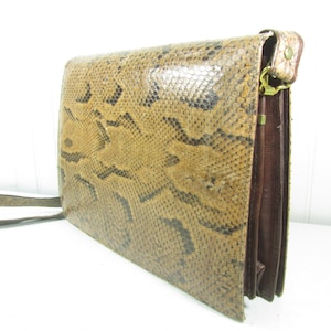 May include: A brown leather satchel bag with a snakeskin pattern. The bag has a long strap and a flap closure.
