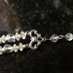 May include: A silver and crystal necklace with a decorative clasp. The necklace is made of two strands of clear crystal beads.