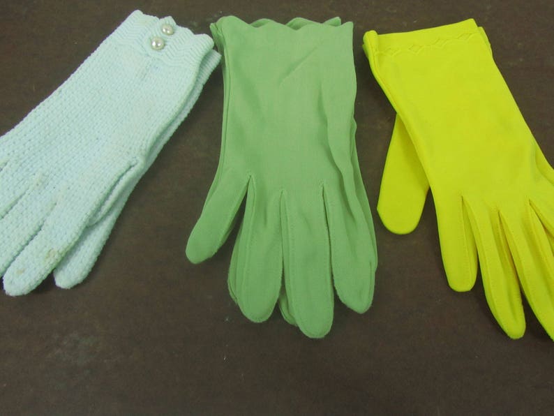 May include: Three pairs of gloves in different colors: light blue, green, and yellow. The gloves are made of a soft, smooth fabric.