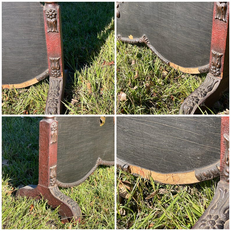 May include: An antique, dark-colored, decorative screen with a red and brown frame. The screen has ornate carvings on the legs and frame. The screen is set on a grassy surface.
