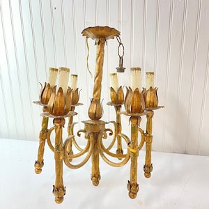 Pode incluir: Um candeeiro de teto de metal dourado com seis luzes. O candeeiro de teto tem um design de metal torcido e cada luz &eacute; cercada por uma pe&ccedil;a de metal em forma de flor.