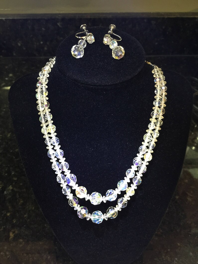 May include: A two-strand crystal necklace with a matching pair of clip-on earrings. The necklace features faceted crystal beads and the earrings have a teardrop shape.