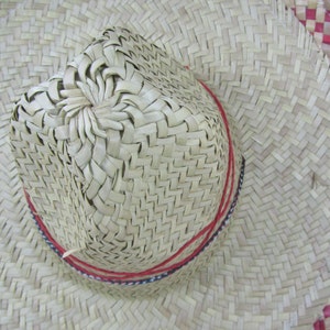 May include: A woven straw hat with a red and white trim. The hat has a wide brim and a pointed crown.