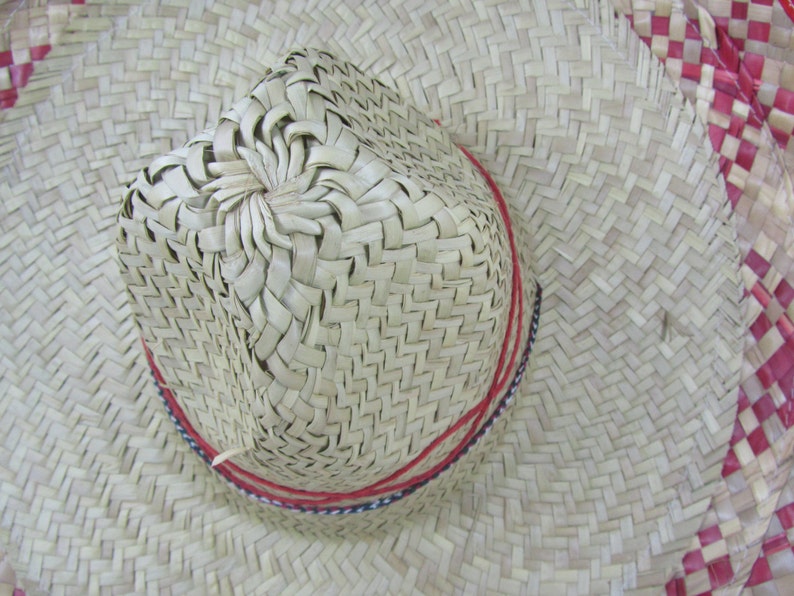 May include: A woven straw hat with a red and white trim. The hat has a wide brim and a pointed crown.