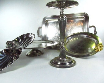 May include: Set of five silver serving dishes, including a round cake stand, a rectangular tray, a small oval dish, and two shell-shaped dishes.